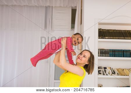 happy family. Mother throws up baby, playing at home.