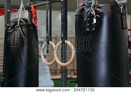 Black Punching Bag and Cross--fit Fitness Rings: Workout Equipment in Gym