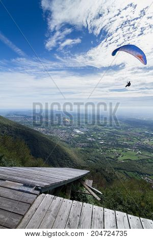 Para-gliders flying in the sky with a ramp for hang gliders and the plain as background