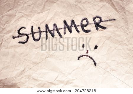 Pity smily on crumpled paper texture. Strikeout summer word. Autumn came and summer ended.