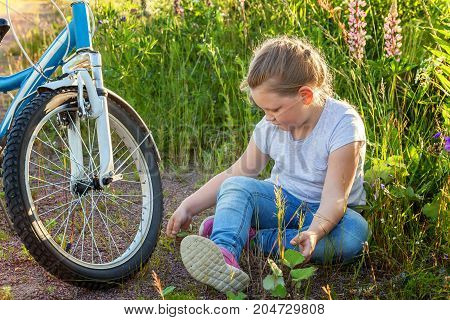 Beautiful smiling girl issitting near the bicycle in the park