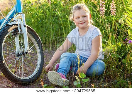 Beautiful smiling girl issitting near the bicycle in the park