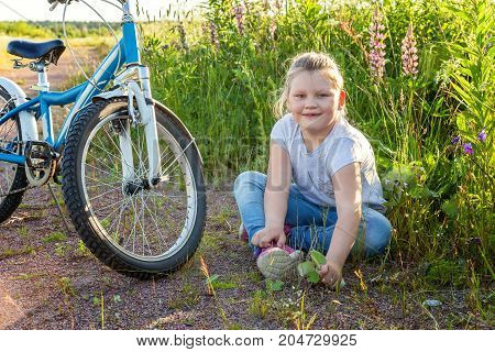 Beautiful smiling girl issitting near the bicycle in the park