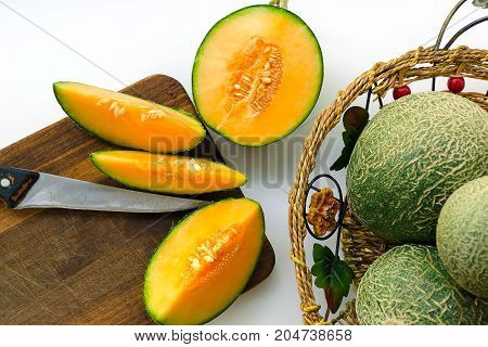 Crop of melons with a green bark and an orange midst. Melons are whole and cut in half.