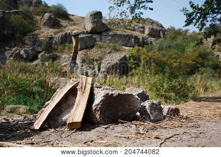 Friends prepared firewood for the fire. A beautiful view of nature against the background of a fire. Summer travels to nature. A great pastime in the summer. The knife sticks out in a piece of wood.
