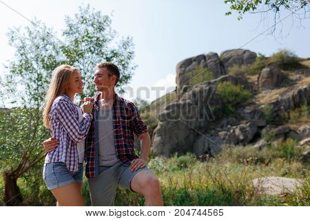 A young couple is traveling in the mountains. Summer journey of lovers, a guy frying meat at a bonfire for a girl. Healthy way of life, travel, summer vacation. The best pastime in the summer.