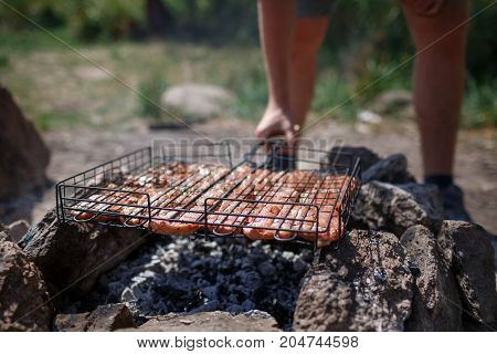 A young couple is traveling in the mountains. Summer journey of lovers, a guy frying meat at a bonfire for a girl. Healthy way of life, travel, summer vacation. The best pastime in the summer.