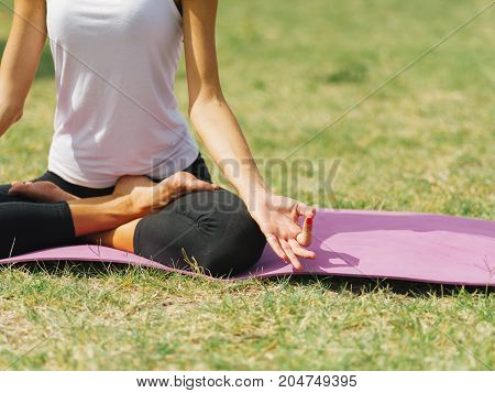 Close-up image of body parts girl's meditation at the health club outside with personal trainer, learning the correct form.