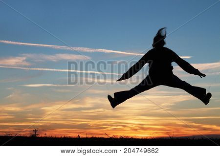 a woman jumping for joy at sunset.