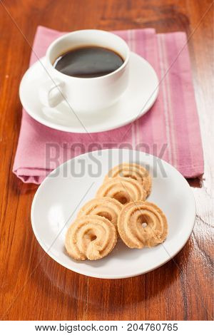 Round shaped cookie and coffee on table.