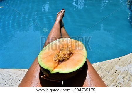 feet in the pool and melon on the legs. juicy melon. summer day. fruits pool. fruits and sea. vacation time. swimming pool. swimming pool food. healthy fruit. spa vacation. travel concept. relax time