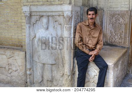 Fars Province Shiraz Iran - 18 april 2017: One mature man is sitting near the facade bas-relief.