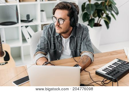 thoughtful young musician working with laptop and MPC pad