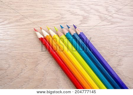 Different colored pencils photo with space for text. Seven pencils of rainbow colors lie on the table. Copyspace. Back to school. Wooden background.