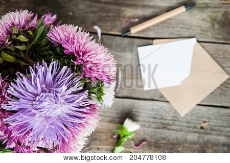 Top View Multicolor Aster Flowers Bouquet, Pen, Blank White Greeting Card And Craft Paper Envelope O