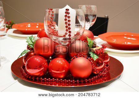 Cristhmas table in Italy with red balls, candle and pearls