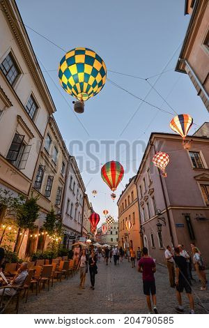 Lublin, Poland - August 10, 2017: Beautiful evening street, glowing balloons and old bright buildings in the old town of Lublin, Poland. Brama street, Lublin. Mountebanks Carnival in Lublin old town.