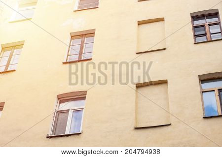 Windows on yellow wall of european appartments. Empty windows among others. Flats without windows