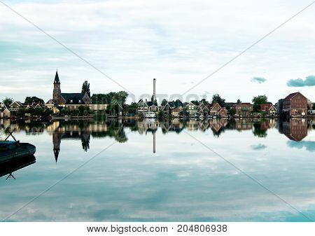 Houses and Church of Zaanse Schans on River Coast with Reflection Early Morning Outdoors. Netherlands