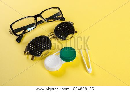 A set of accessories for sight. Pinhole glasses lenses with container and glasses for sight. Pair of medical pinhole glasses with reflections. Medical concept. Top view.