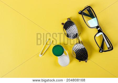 A set of accessories for sight. Pinhole glasses lenses with container and glasses for sight. Pair of medical pinhole glasses with reflections. Medical concept. Top view.