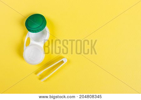 Container for contact lenses tweezers yellow table