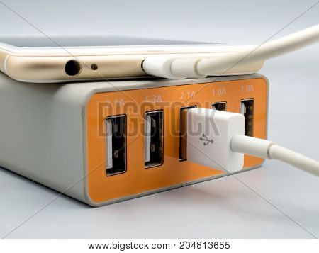 Close-up image of smart phone charging with multiport USB power adaptor on gray background Selective focus