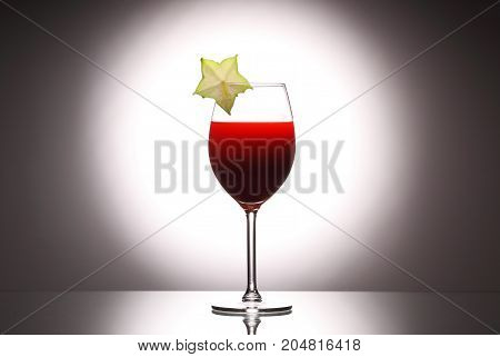 Wineglass Red Liquid Cocktail Decorated With Green Carambola On Studio Background.