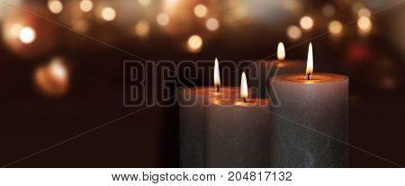 Burning candles on a dark background with golden lights