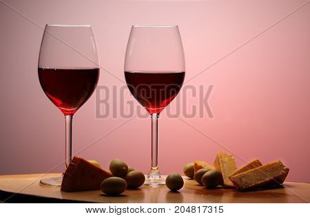 Wineglasses With Red Wine On Wood With Cheese And Green Olives. Studio Background.