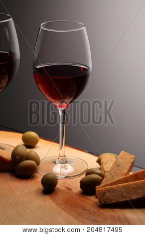 Wineglasses With Red Wine On Wood With Cheese And Green Olives. Studio Background
