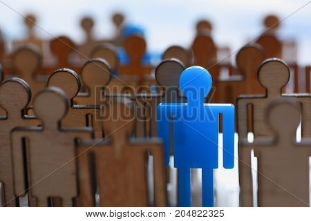 Figurine blue man in the crowd of wooden figures of ordinary people stands out from the rally as leader leader massone moves society politician special advantageous difference