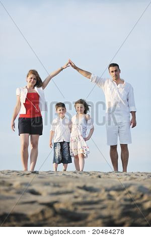 happy young family have fun on beachand showing home sign with conncected hands while protecting childrens