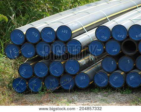 Gas line pipe ready to be installed in a neighborhood. The digging equipment is nearby.