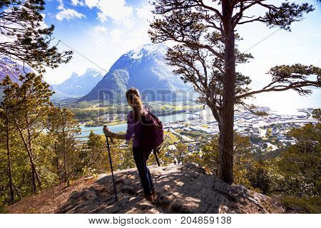Rampestreken - girl hiker with a backpack and trekking pole standing and looking on Romsdalsfjorden and Andalsnes Norway