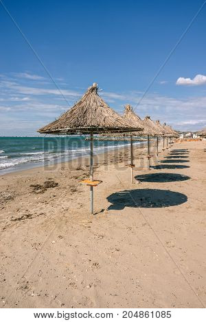 Albania. Golem. Beach shoreline with sun umbrellas made from straw. A blue sky on the Adriatic Sea.