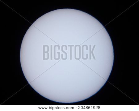 the sun viewed through a solar filter in a telescope with sunspot visible