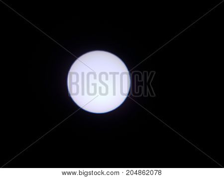 the sun viewed through a solar filter in a telescope with sunspot visible
