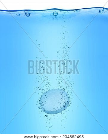 Medical pill close-up dissolves in blue water
