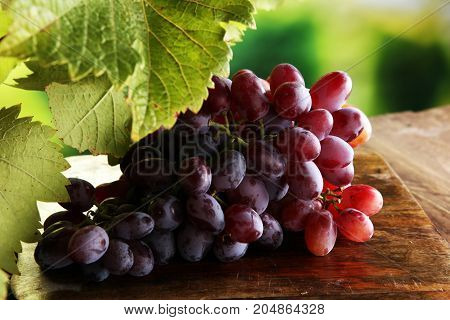 Grapes on wooden table and grape leaves . Healthy fresh fruit wine grapes.