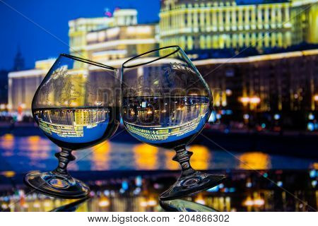 Two glasses with liquid on glass table night city background