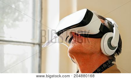 Senior old man wearing VR headset and enjoying virtual reality digital world. Virtual and augmented reality are increasingly used in human lives.