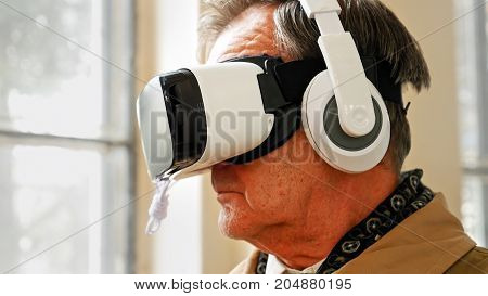 Senior old man wearing VR headset and enjoying virtual reality digital world. Virtual and augmented reality are increasingly used in human lives.
