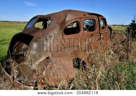 Remains of the frame of a very old dilapidated and rusty car,