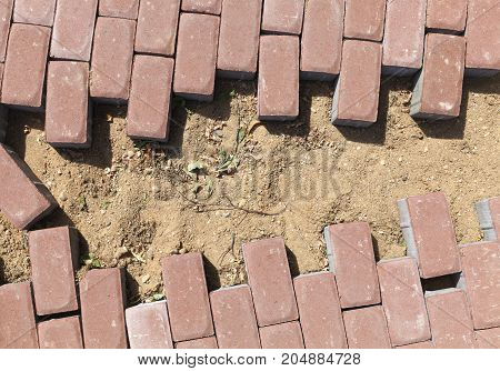 Paving The New Footpath Of Cobbles Of Red Color. The Place Of Docking And Joining The Building Mater