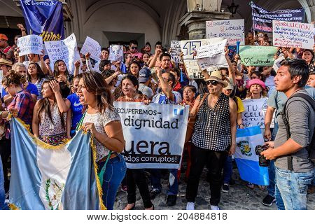Antigua Guatemala - September 15 2017: Locals wave Guatemalan flags & slogans protesting against government corruption in front of city hall on Guatemala's Independence Day.
