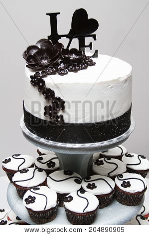 a white and black wedding cake with love on top.