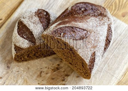Two Halves Of Black Aromatic Bread Baked From Rye Flour. The Loaf Is Cut Into Two Halves During Cook