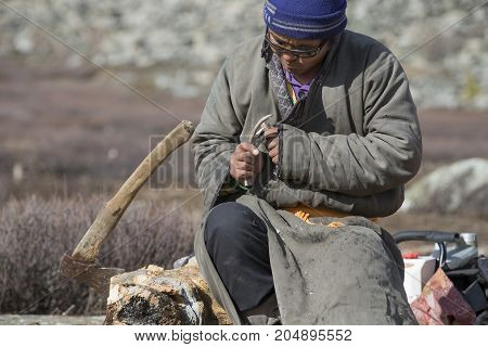 tsaatan man carving a reindeer horn outdoors in northern Mongolia