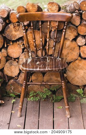 old vintage chair made of wood on the background of wood logs firewood